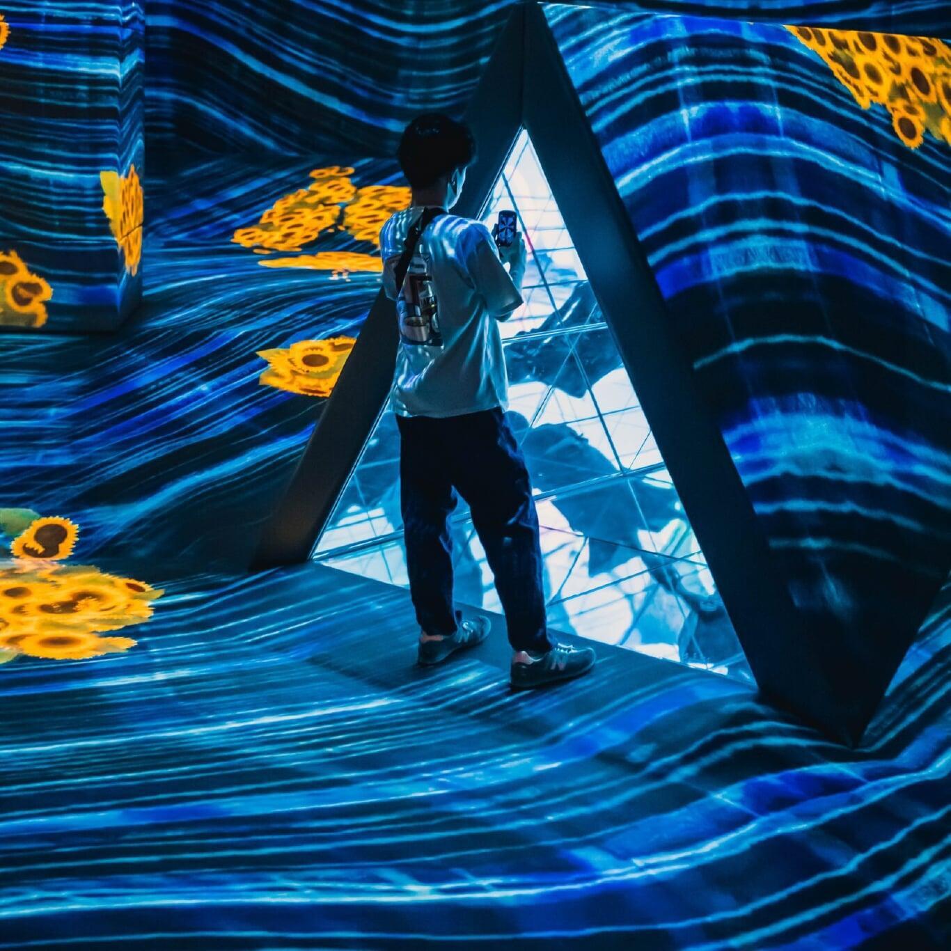 Enfant qui interagit avec une technologie immersive dans lieu dédié aux expériences de ce type comme en atteste l‘ambiance très colorée de la photo